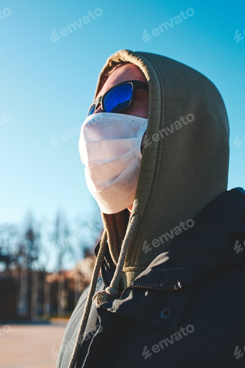 Preview: Young man in the hood wearing the face mask to avoid virus infection and to prevent the spread of