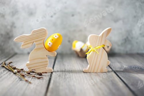 Preview: Easter wooden bunnies and Easter colored eggs on a wooden table. Festive Home Decor