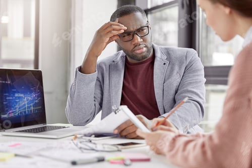 Preview: Dark skinned director of corporation listens with puzzled expression female employee, can`t understa