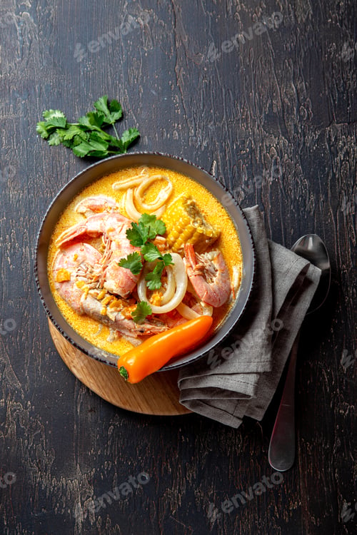 Preview: Peruvian seafood soup Chupe de Camarones in gray bowl, top view.