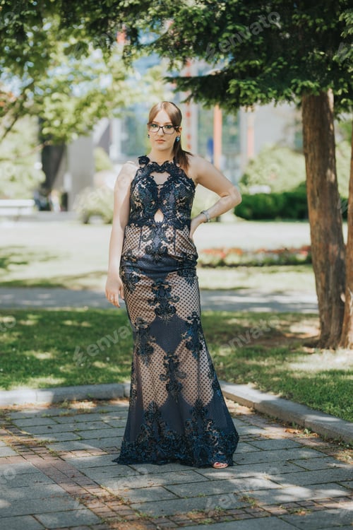 Preview: Beautiful Caucasian young female in an elegant long cream dress with black lace posing in a park
