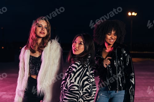 Preview: Fashionable girls standing together on roof at night under neon lights