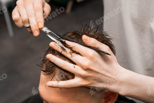Preview: Barber uses scissors and comb to style the mans hair at the barbershop.