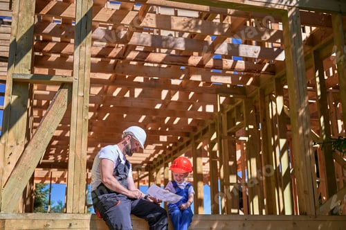 Preview: Father teaching his toddler son the art building wooden frame house on construction site.