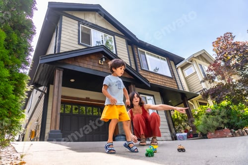 Aperçu: Mother and son playing with toy cars in front of house