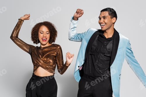 Preview: excited african american couple in elegant clothes dancing on christmas party isolated on grey