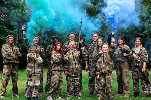 Preview: People in camouflage celebrating winning laser tag shooting game with colored smoke. N