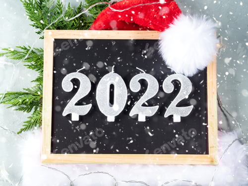 Visualização: Números do ano novo de 2022 no quadro-negro com boné de Papai Noel e galhos de abeto em cinza com luzes estelares