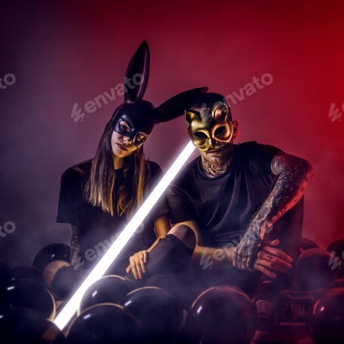Preview: Young people sitting with car and rabbit masks and a light lamp and black balloons