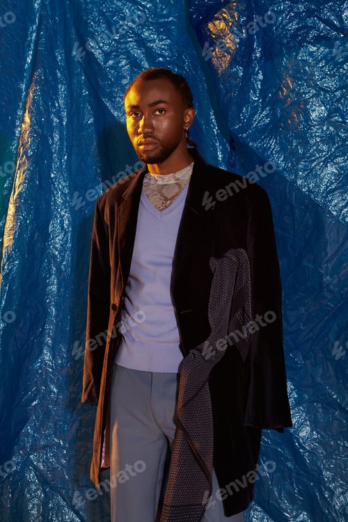 Preview: Handsome young man poses confidently against a vibrant blue backdrop showcasing modern style