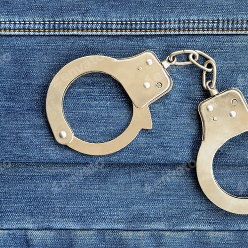 Preview: Police steel handcuffs lying on dark blue jeans background