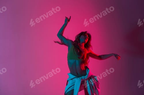 Preview: Pretty dancer woman in stylish wear in trendy shoes dancing with colorful light. Sporty girl