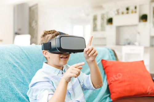 Preview: Caucasian boy sitting on couch and using vr headset in living room