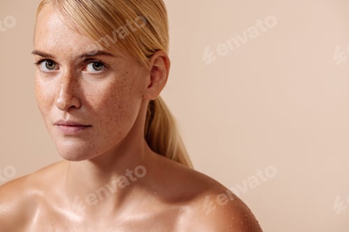 Preview: Beauty portrait of a young blond woman. Female with freckles looking straight of a camera.