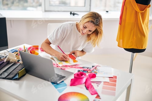 Preview: Smiling fashion designer sketching with a pencil