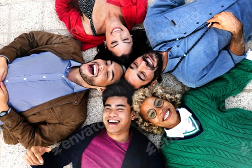 Preview: Happy multiracial friends lying down with heads touching forming a circle.