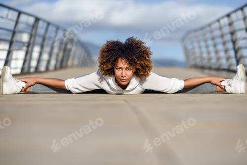 Preview: Young black woman doing stretching after running outdoors