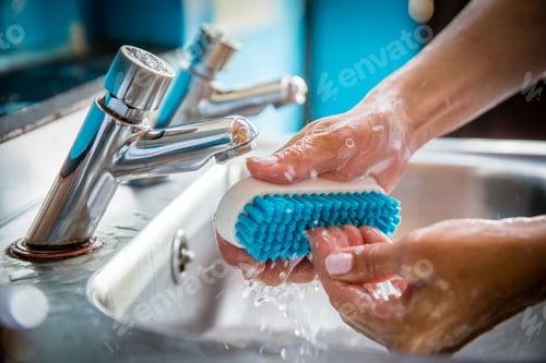 Preview: Hands scrubbing with soap under running water at the sink.