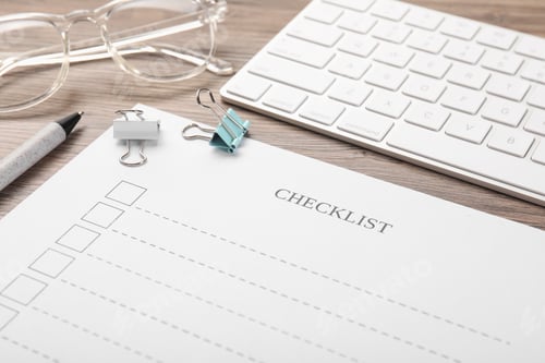 Preview: Checklist, pen, glasses, paper clips and keyboard on wooden table, closeup