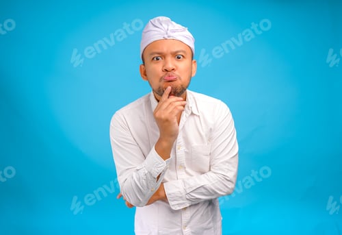 Preview: Confused Balinese man in traditional udeng thinking hard with serious expression.