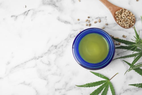 Preview: Jar of hemp cream and seeds on marble table, flat lay with space for text. Organic cosmetics