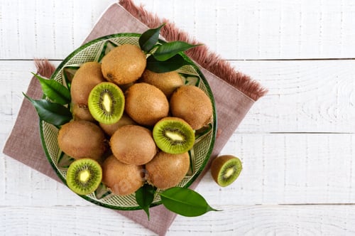 Preview: Ripe kiwi fruit in a bowl on a white wooden background. The top view