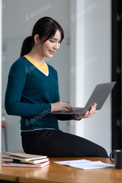 Preview: Happy young asian woman using laptop to browse internet.