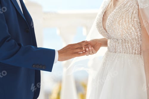 Preview: Woman putting engagement ring on man hand at wedding ceremony