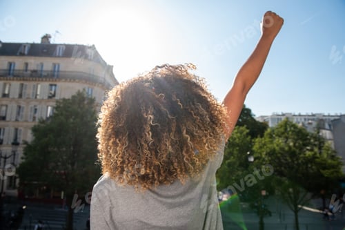 Preview: behind young african american woman with arm raised fist