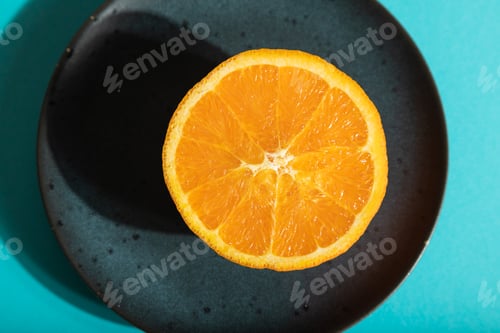 Preview: Ripe cut orange on blue ceramic plate on blue pastel background. Top view, close up, hard light.