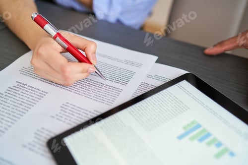 Preview: A person is writing on a piece of paper with a red pen