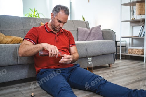 Preview: Mature man sitting on the floor and drinking alcohol