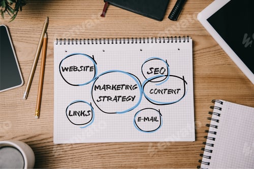 Preview: top view of business supplies, digital devices and notebook with marketing strategy on workplace