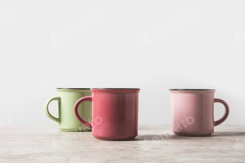 Preview: three colored cups on marble table on white