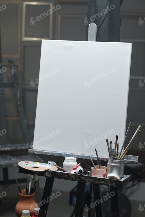 Preview: Blank sheet of paper on easel with color palette, jars and jug with paintbrushes