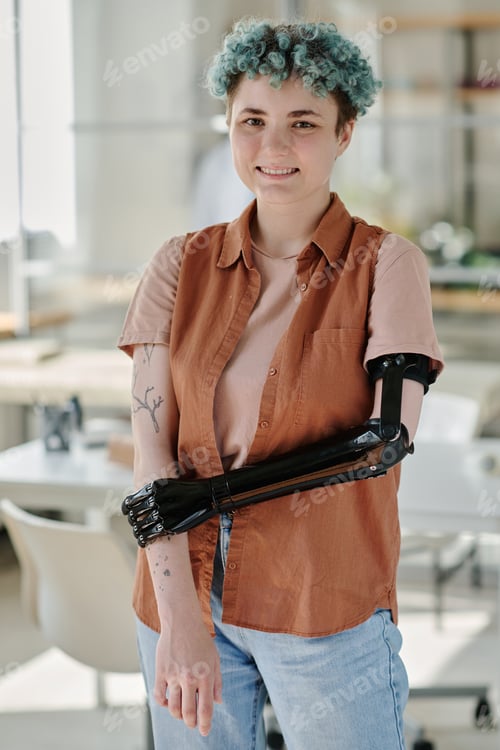 Preview: Young girl with prosthetic arm smiling at camera in doctors office