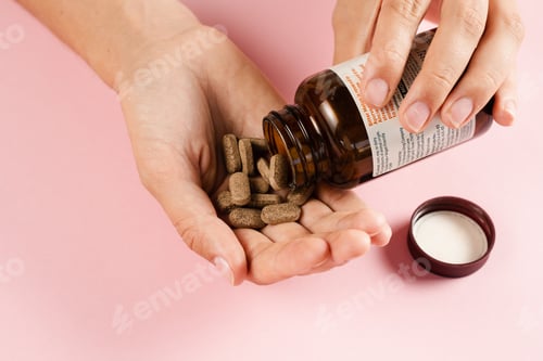 Preview: Hand holding zinc pills, antioxidants, lecithin, adaptogen on pink background