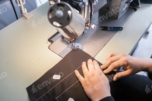 Preview: Female fashion designer using sewing machine in jeans factory