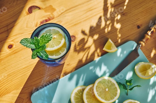 Preview: Summer refreshing lemonade drink with mint, ice and lemon slices on wooden table.