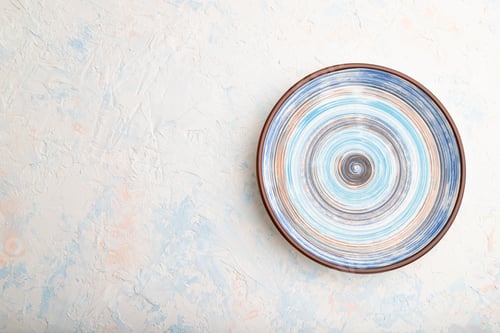 Preview: Empty blue ceramic plate on white concrete background. Top view, copy space.