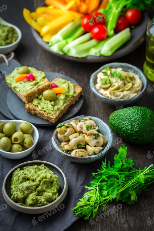 Preview: Vegan raw food snacks with fresh juicy vegetables, avocado dip and humus