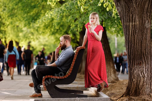 Preview: Young loving hipster couple eating ice cream outdoors at city crowded street. Stylish smiling bearde