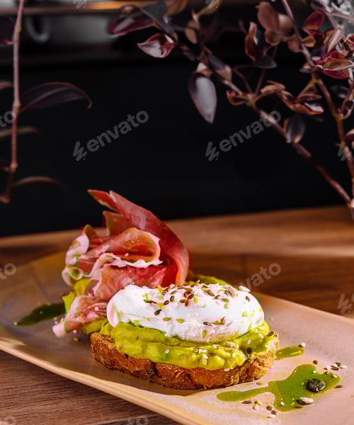 Preview: Delicious toast with avocado spread, poached egg and prosciutto on wooden table
