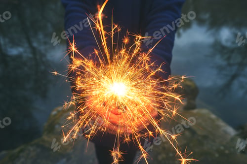 Preview: Woman holding sparkler in forest, winter day