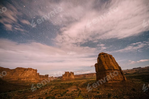 Preview: Clouds in starry sky and valley rock formations at night, Moab, Utah, USA