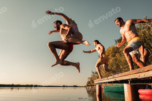 Preview: Group of friends having fun enjoying a summer day swimming and jumping at the lake.