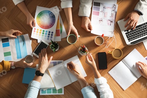 Preview: Team of professional designers working together at table, top view