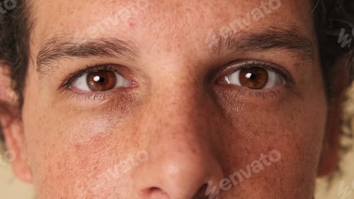 Preview: Detailed close-up shot of man's eye looking at the camera studio on beige background