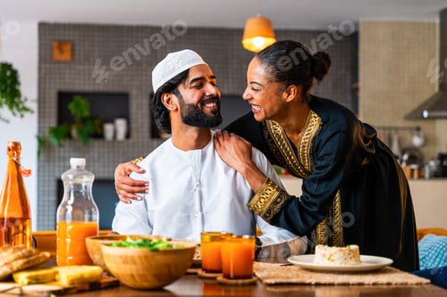 Preview: Happy beautiful young arab couple with emirati clothing having meal together at home