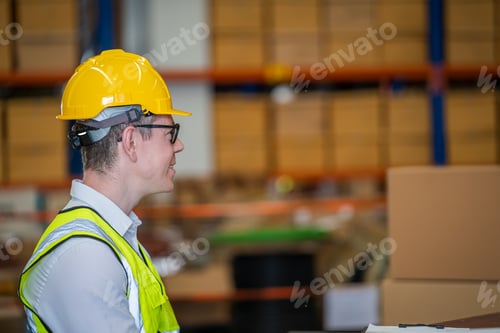Preview: Warehouse worker moving cardboard boxes while working with a colleague in a warehouse,.